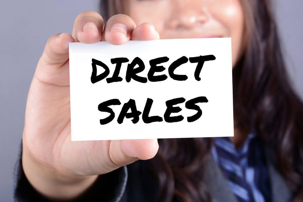 A woman showing a card with a message of "direct sales".